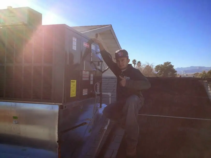 HVAC technician performing AC Tune-Up on a rooftop unit in Springdale